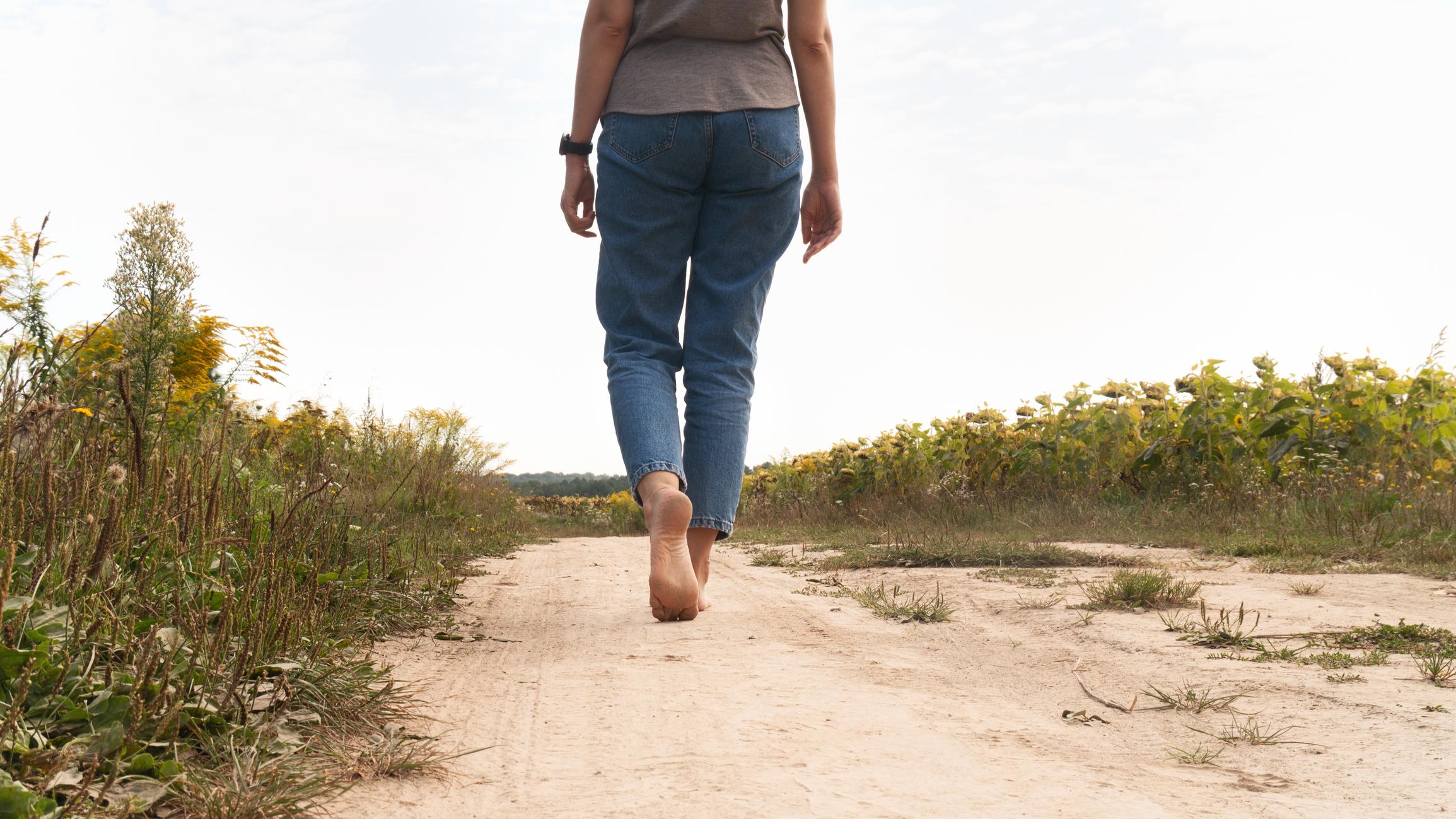 Mujer caminando descalza por un camino de arena