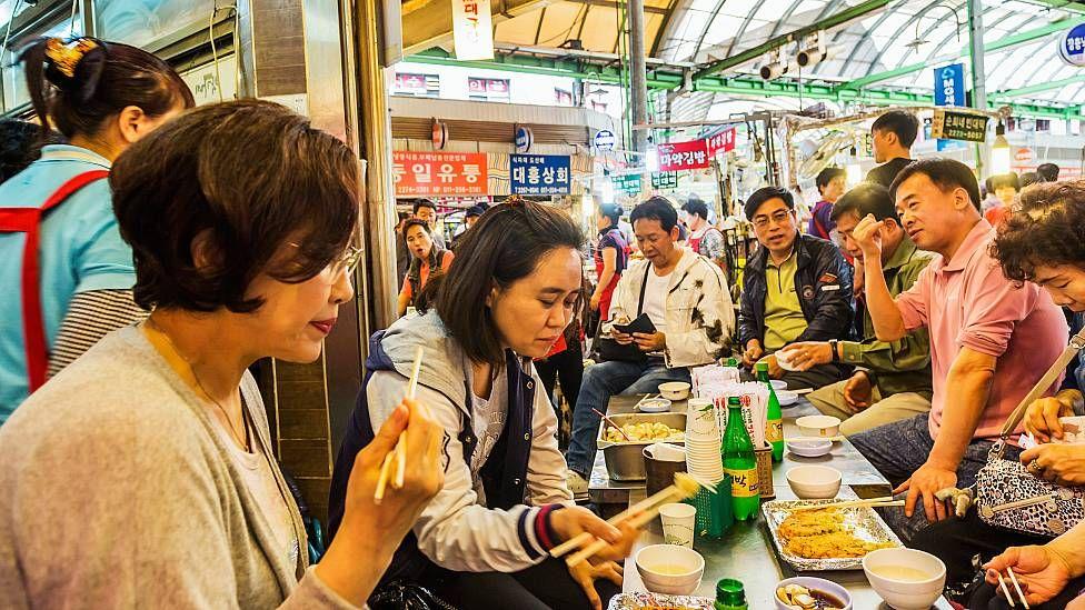 Personas comiendo en mercado en Corea del Sur