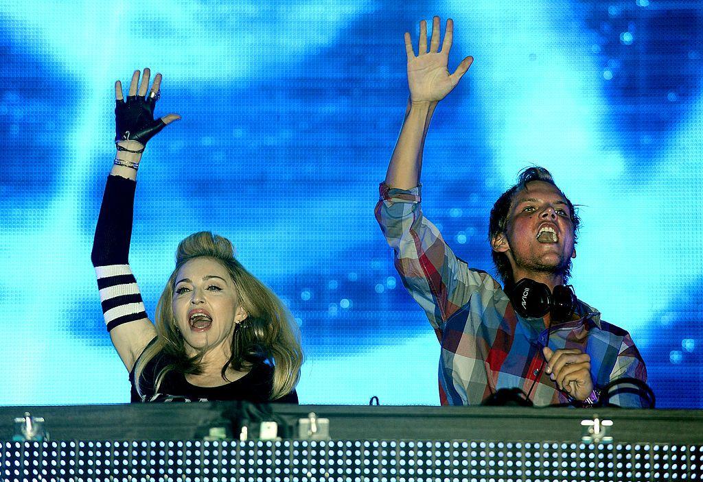 Madonna e Avicii com o braço erguido durante show, cantando e dançando