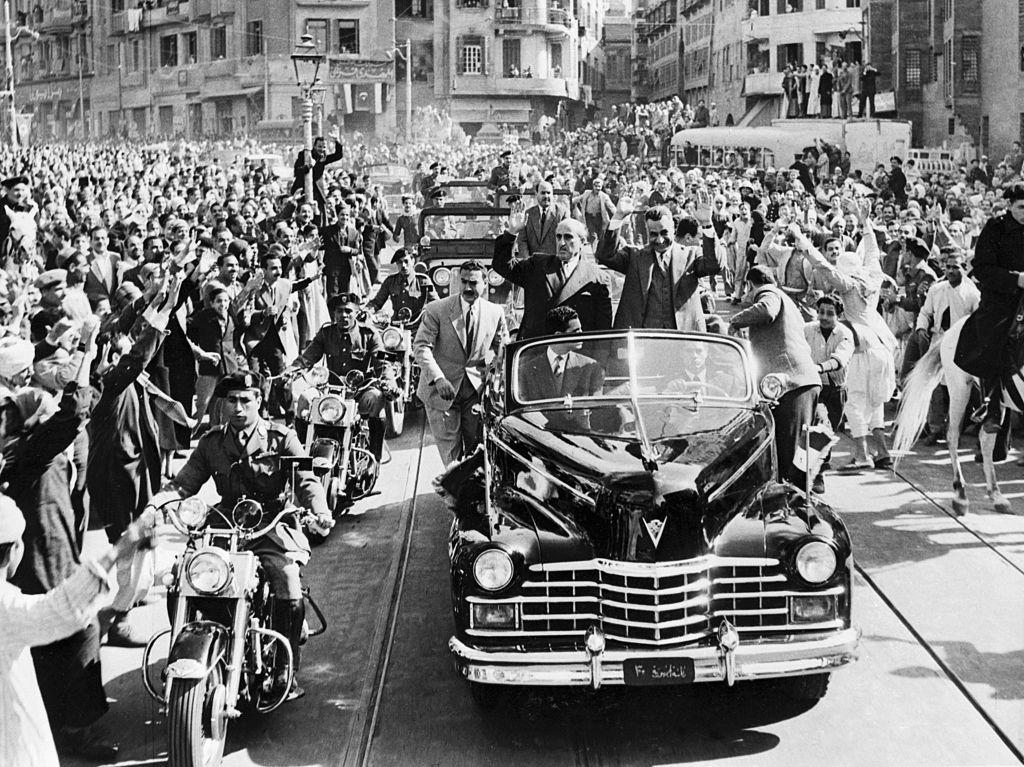 حشود تحيط بالسيارة التي يستقلها الرئيس المصري جمال عبد الناصر (إلى اليمين) والرئيس السوري شكري القوتلي وهما يتجهان للتوقيع على الأوراق النهائية لاندماج مصر وسوريا في دولة عربية موحدة.
