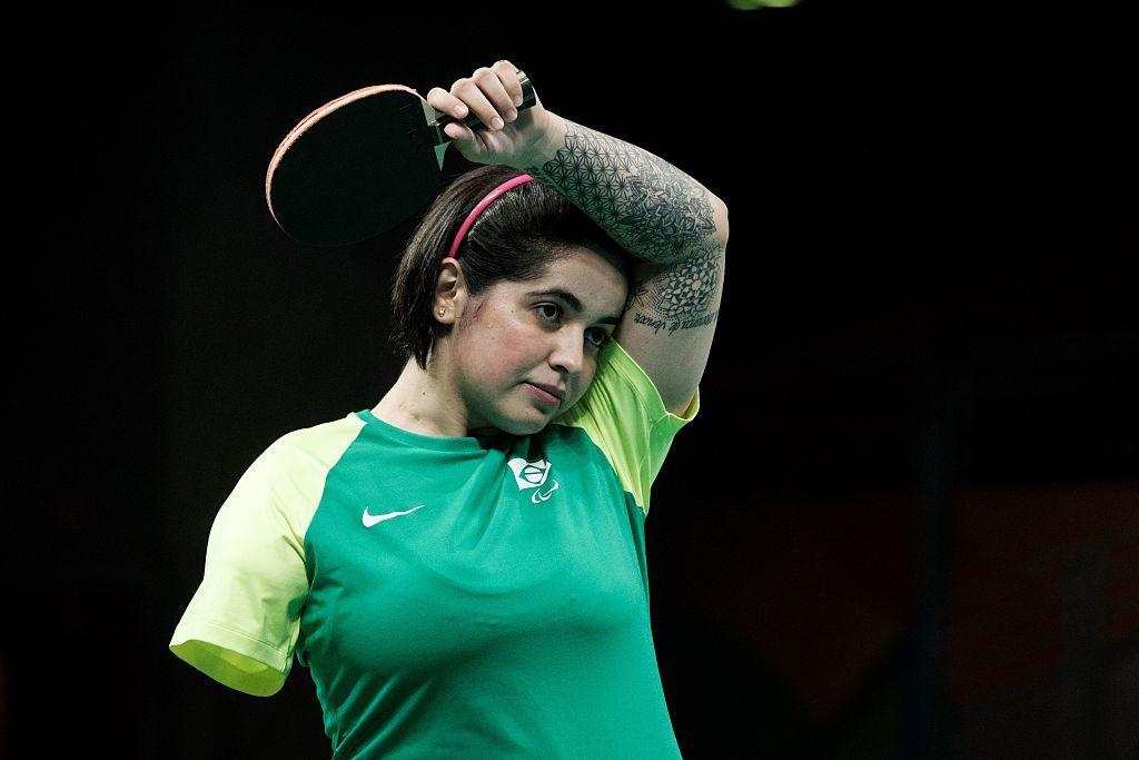 Bruna Costa Alexandre with one arm raised during a game of table tennis. Her right arm is missing. 