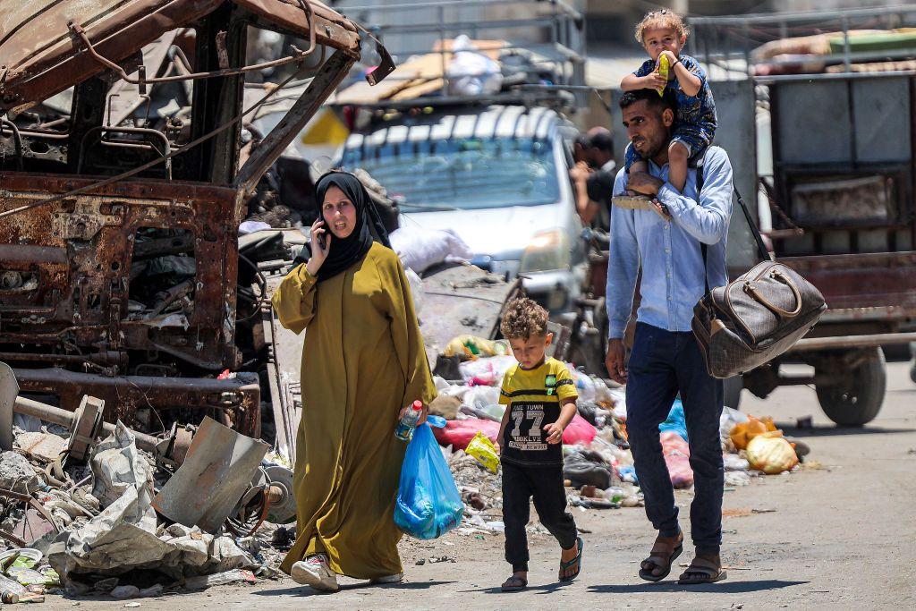 رجل وامرأة يحملون أغراضاً ويصحبون طفلين، مغاردين ضاحية الشجاعية شرق مدينة غزة باتجاه حي الدرج