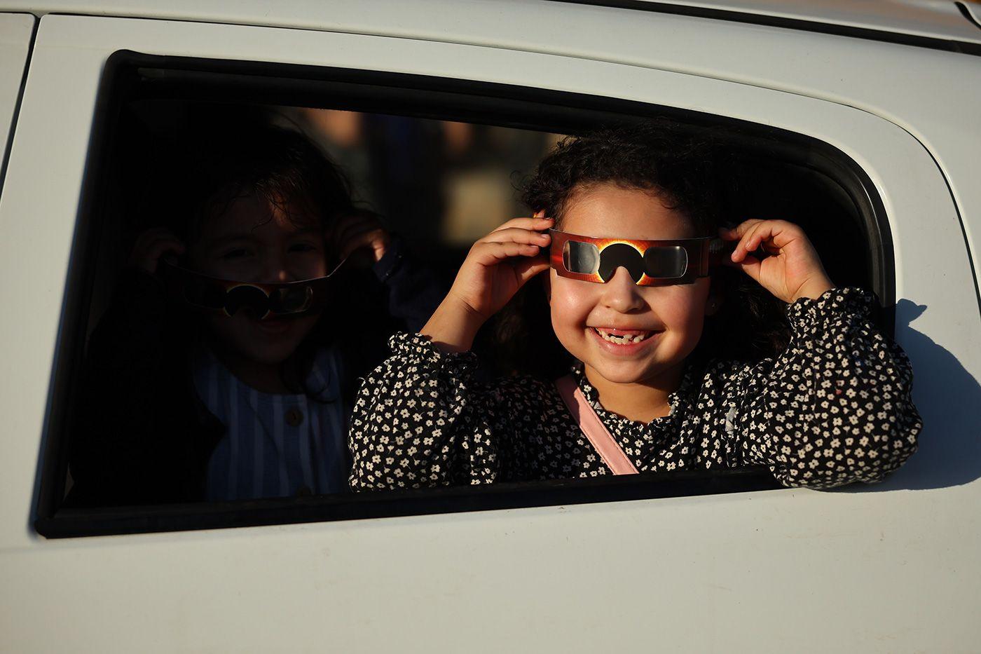 Menina com óculos de proteção observando o eclipse