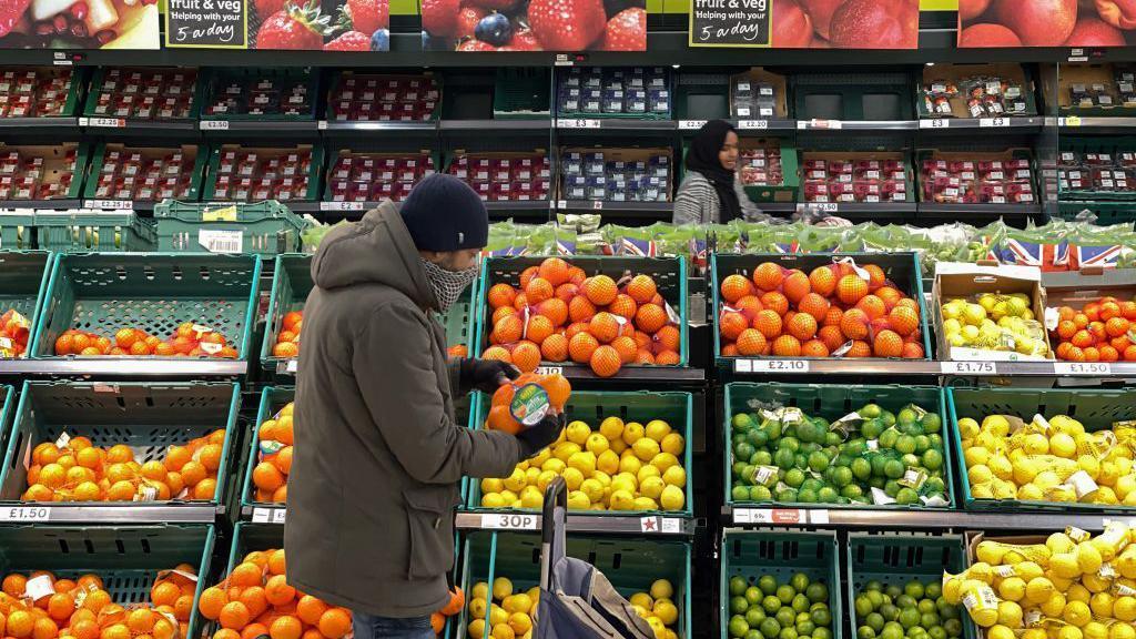 Uma pessoa olhando frutas e legumes em supermercado