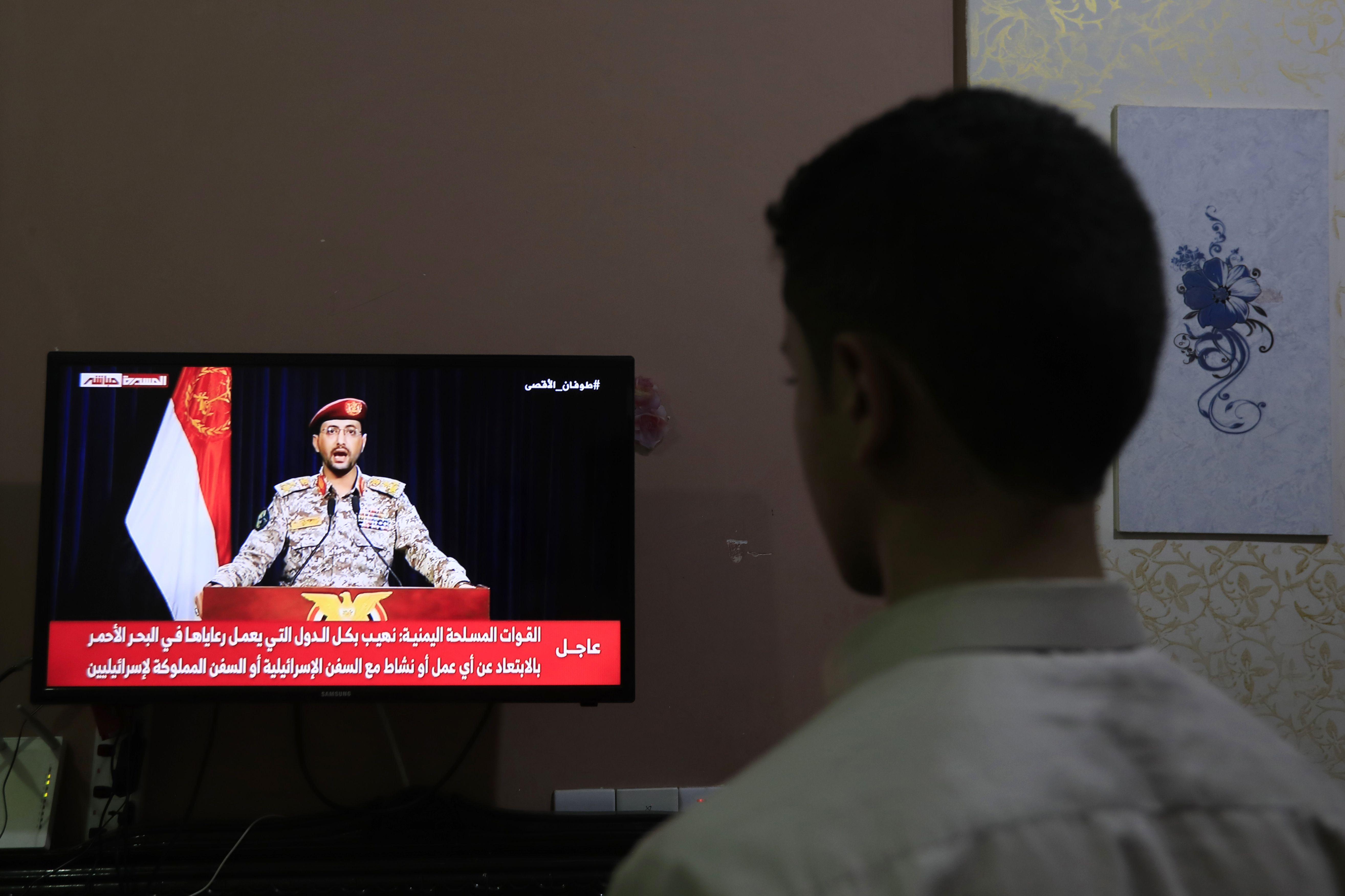 شخص يشاهد بيانًا تلفزيونيًا للمتحدث العسكري للحوثيين يحيى سريع بعد استهداف الحوثيين لسفينة إسرائيلية في البحر الأحمر