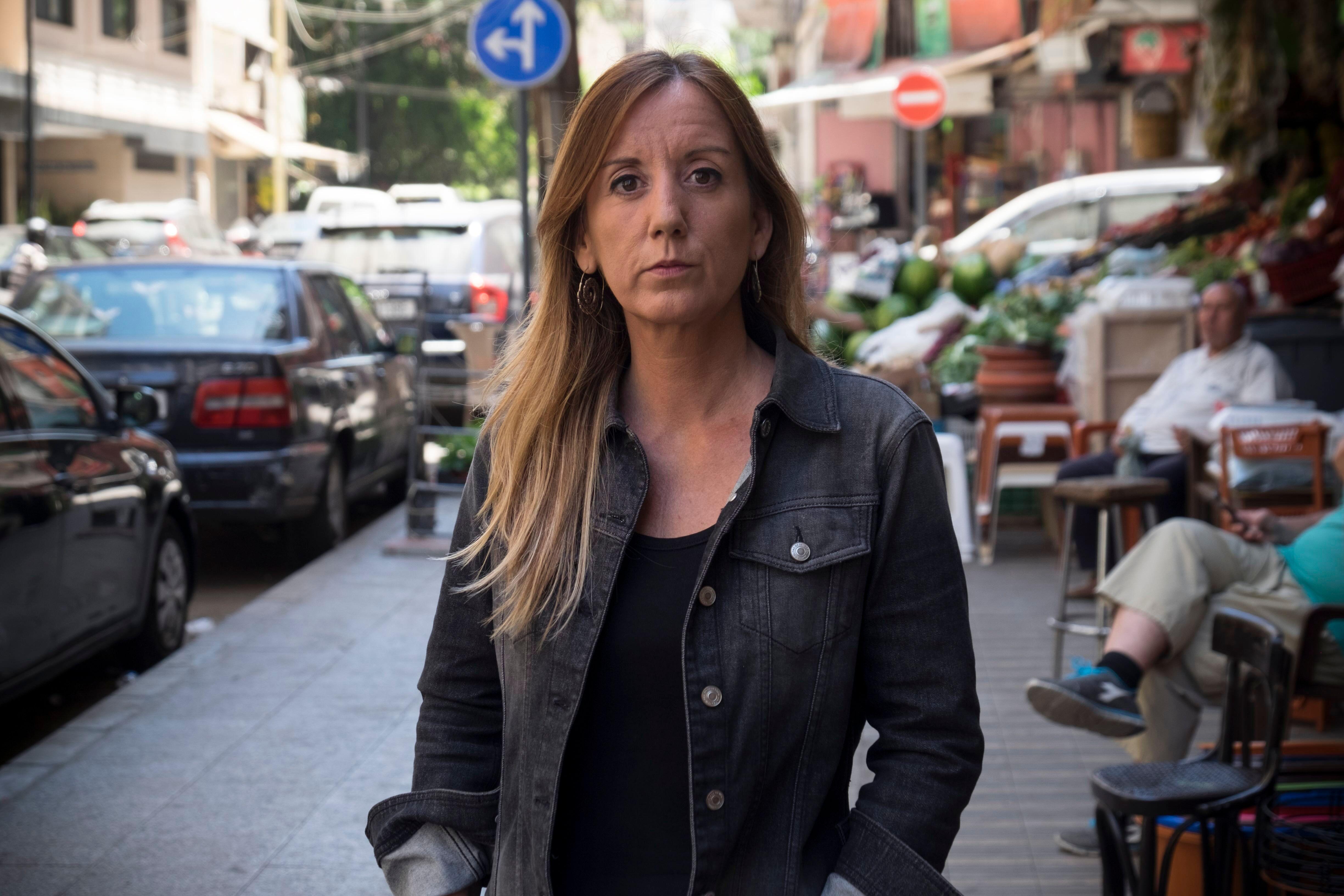 La periodista Feixas Torres mira a la cámara con una chaqueta de jean, en la que parece ser una calle en Medio Oriente.