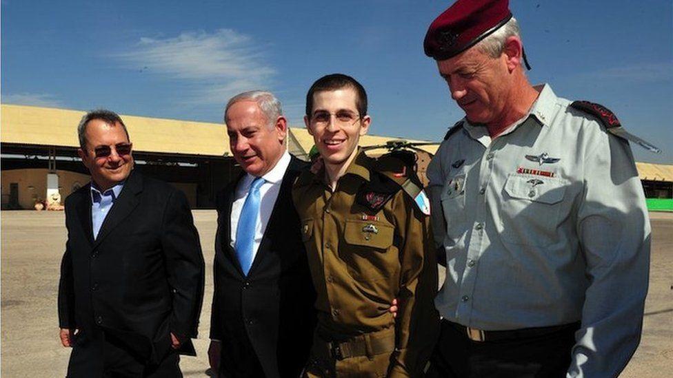 Nesta foto fornecida pela Força de Defesa de Israel, o soldado israelense libertado Gilad Shalit (2º à direita) caminha com o ministro da Defesa Ehud Barak (E), o primeiro-ministro israelense Benjamin Netanyahu (2º, à esquerda) e o chefe do Estado-Maior General das FDI Benny Gantz (D ) na Base Aérea de Tel Nof em 18 de outubro de 2011, no centro de Israel