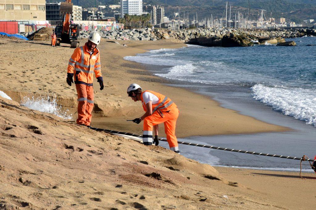 Técnicos verificando um cabo subaquático que chegou à costa