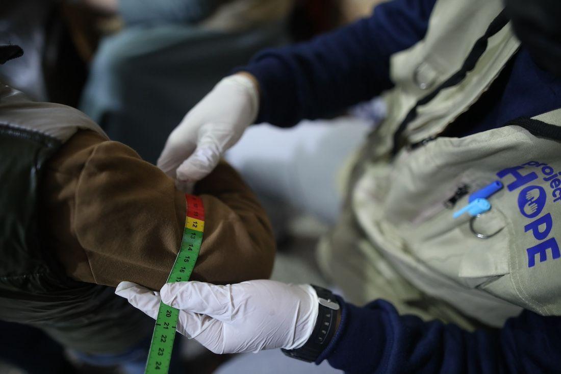 A Project Hope worker measuring a person's arm