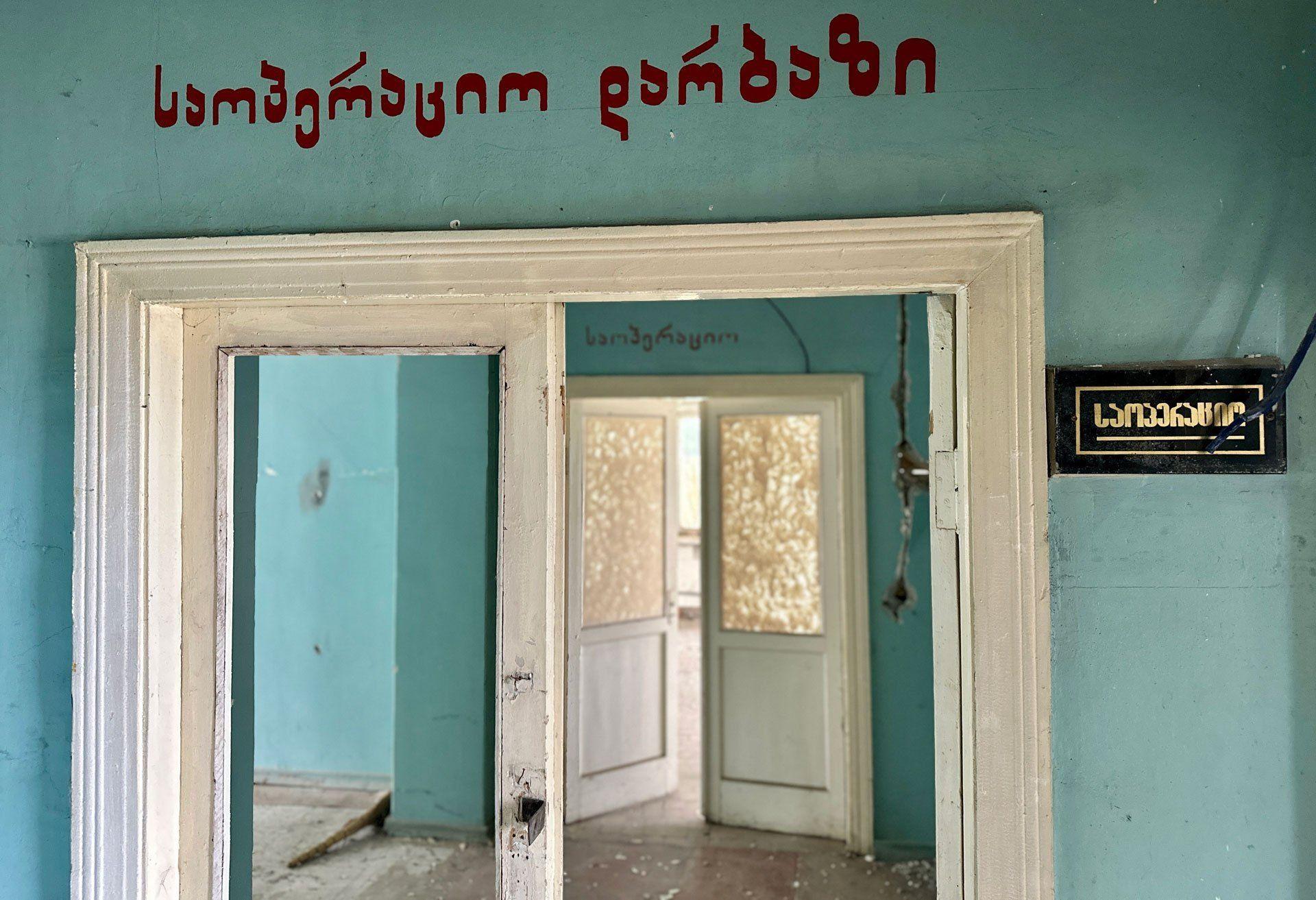 A Georgian sign over a hallway in a derelict hospital