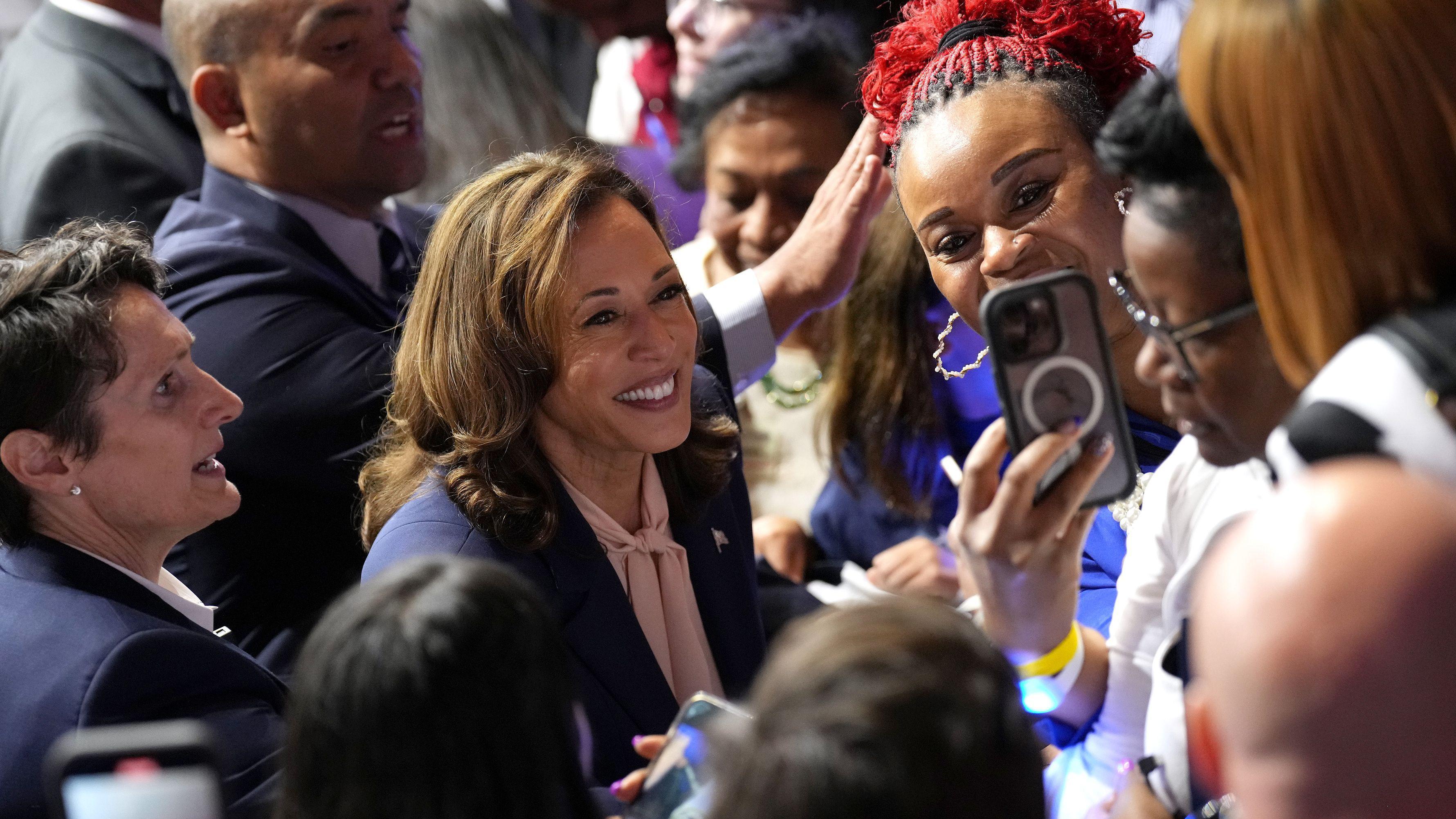 Kamala Harris sorrindo ao lado de um grupo de pessoas durante uma campanha nos EUA