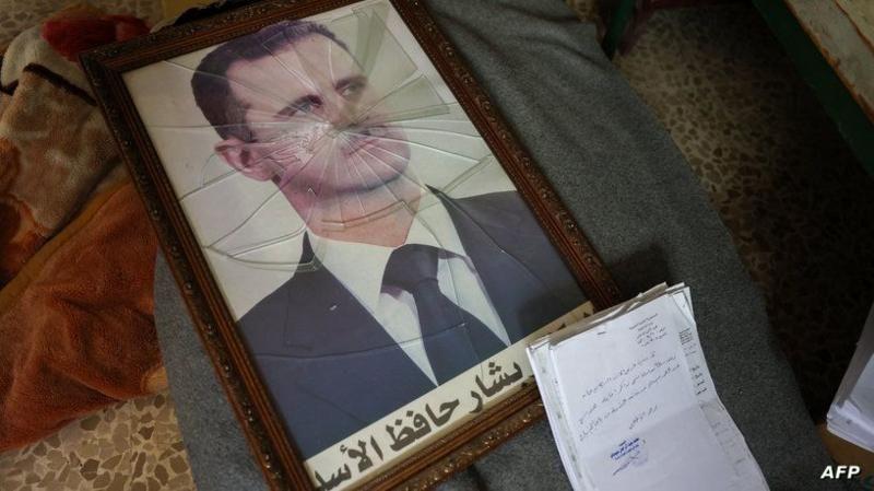 Retrato de Bashar al Assad roto y tirado en el piso. 