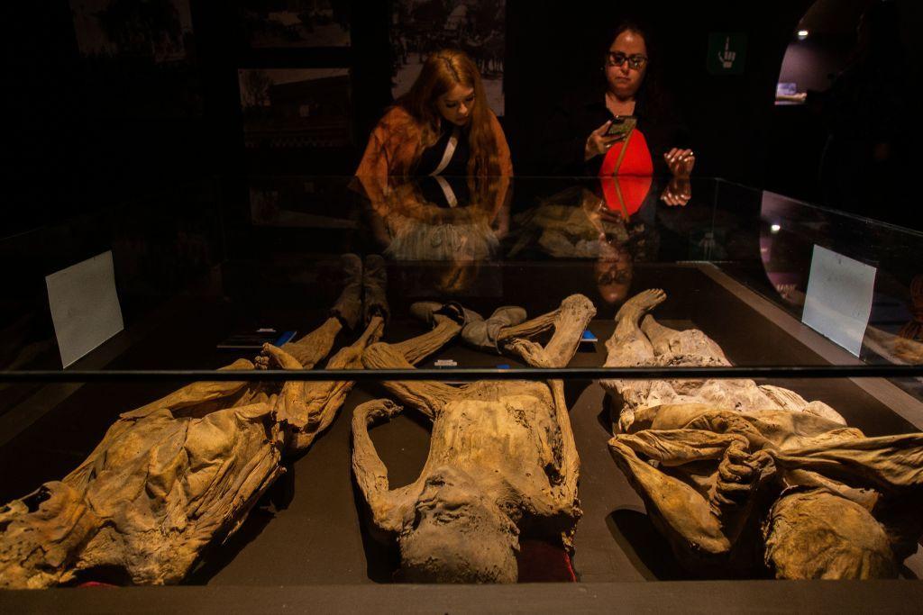 visitantes observan a tres momias en el Museo de las Momias en Guanajuato 