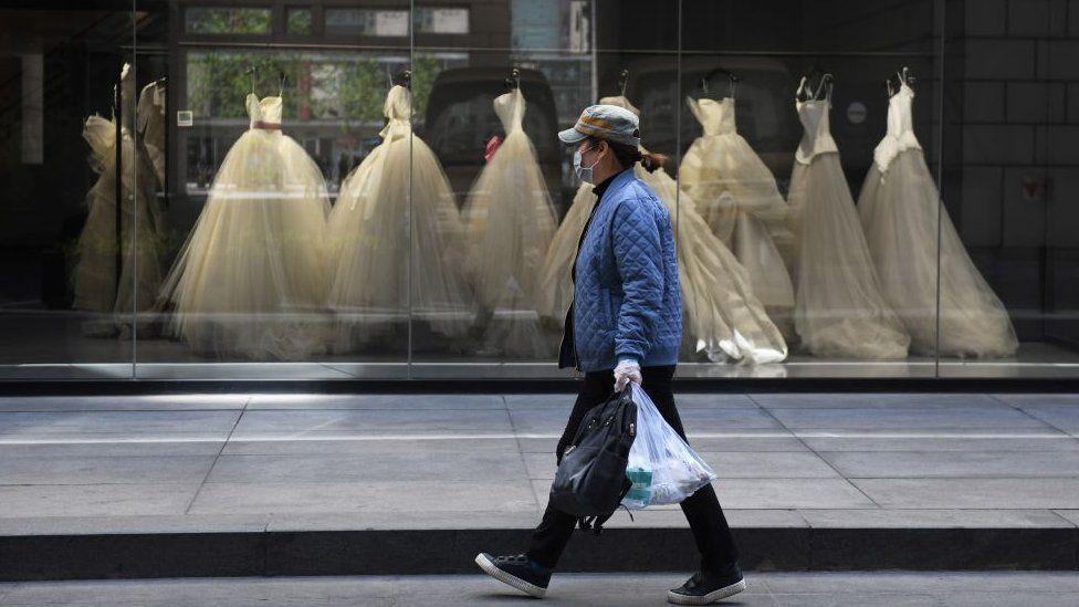 Una mujer camina frente a una tienda de vestidos de novia