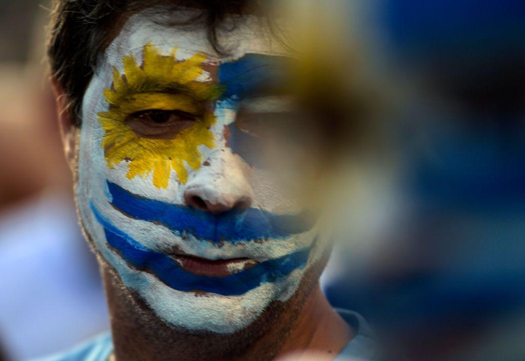 Hombre con la cara pintada con la bandera de Uruguay