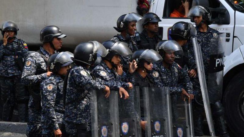 Tropa da Polícia Nacional Bolivariana enfileirada e com escudos