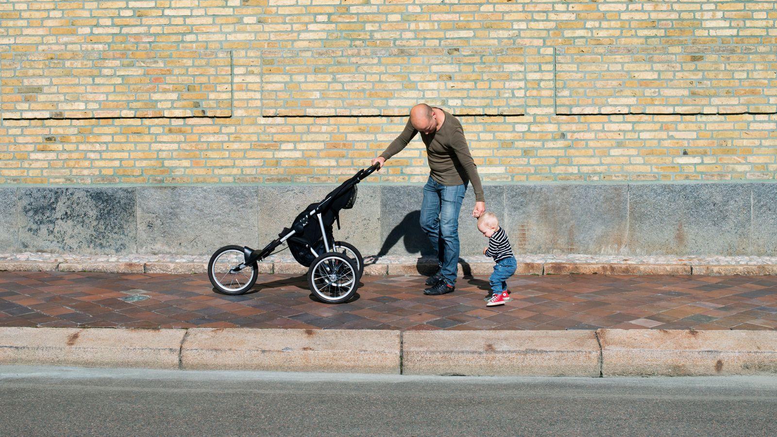 Pai leva carrinho enquanto caminha com filho