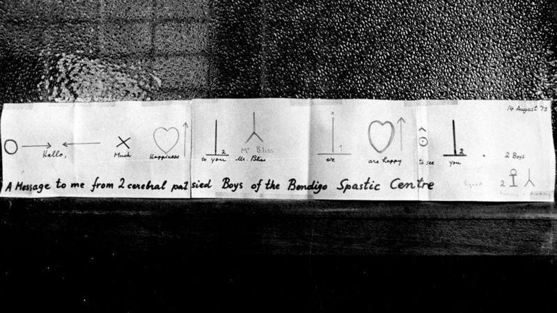 Mensagem em símbolos de Bliss entregue ao seu criador em 1974, assinada por dois meninos com paralisia cerebral do Centro Espástico Bendigo, na Austrália: 