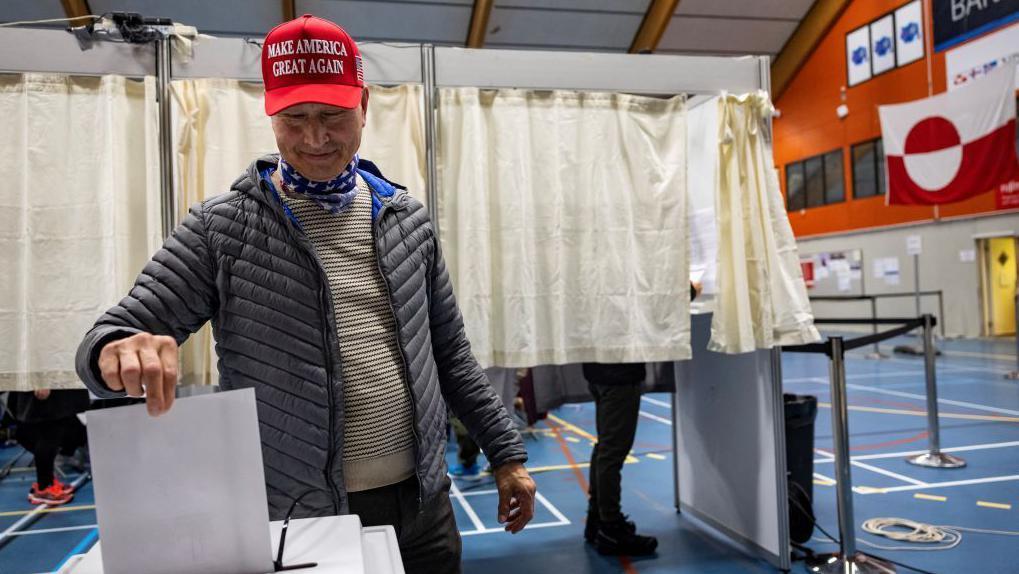 Un hombre con una gorra MAGA deposita su voto en las elecciones de Groenlandia