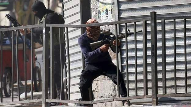 Fighters on a balcony, one pointing his rifle