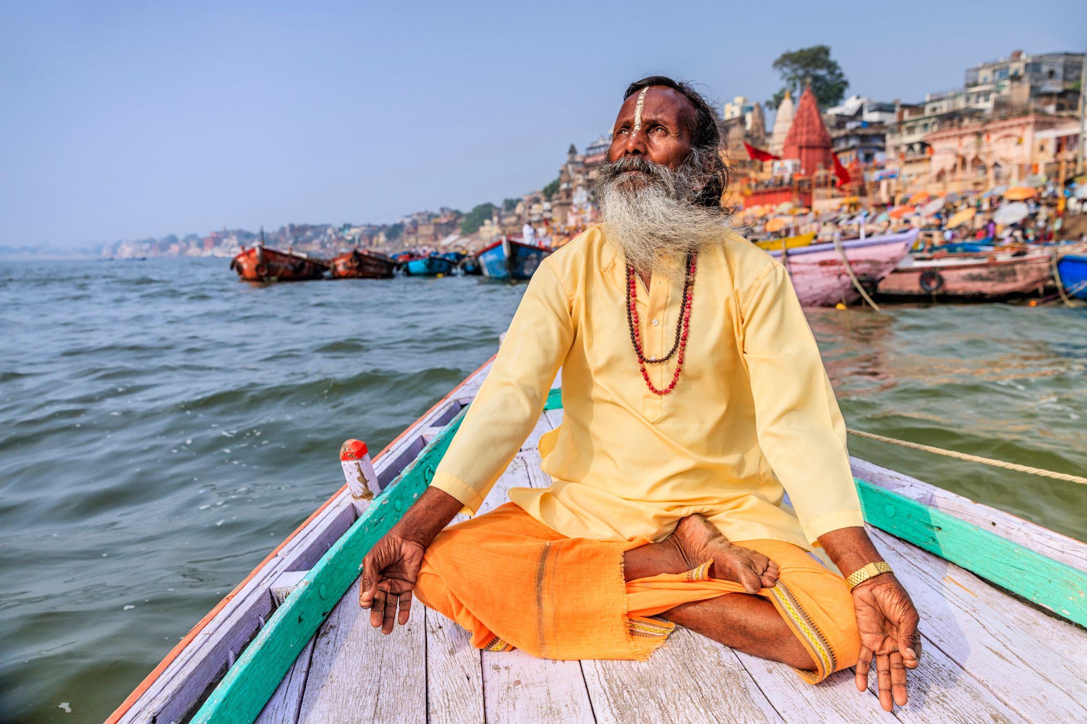 Un hombre practicando yoga en un bote sobre el río Gangés.