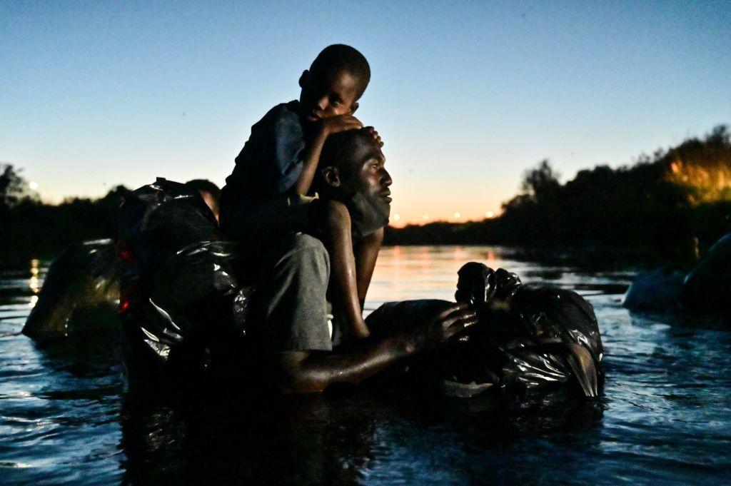 Migrante em rio com seus filhos nos braços