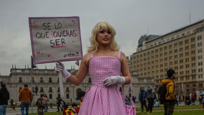 Una mujer sostiene un cartel que dice: "Se lo que quieras ser"