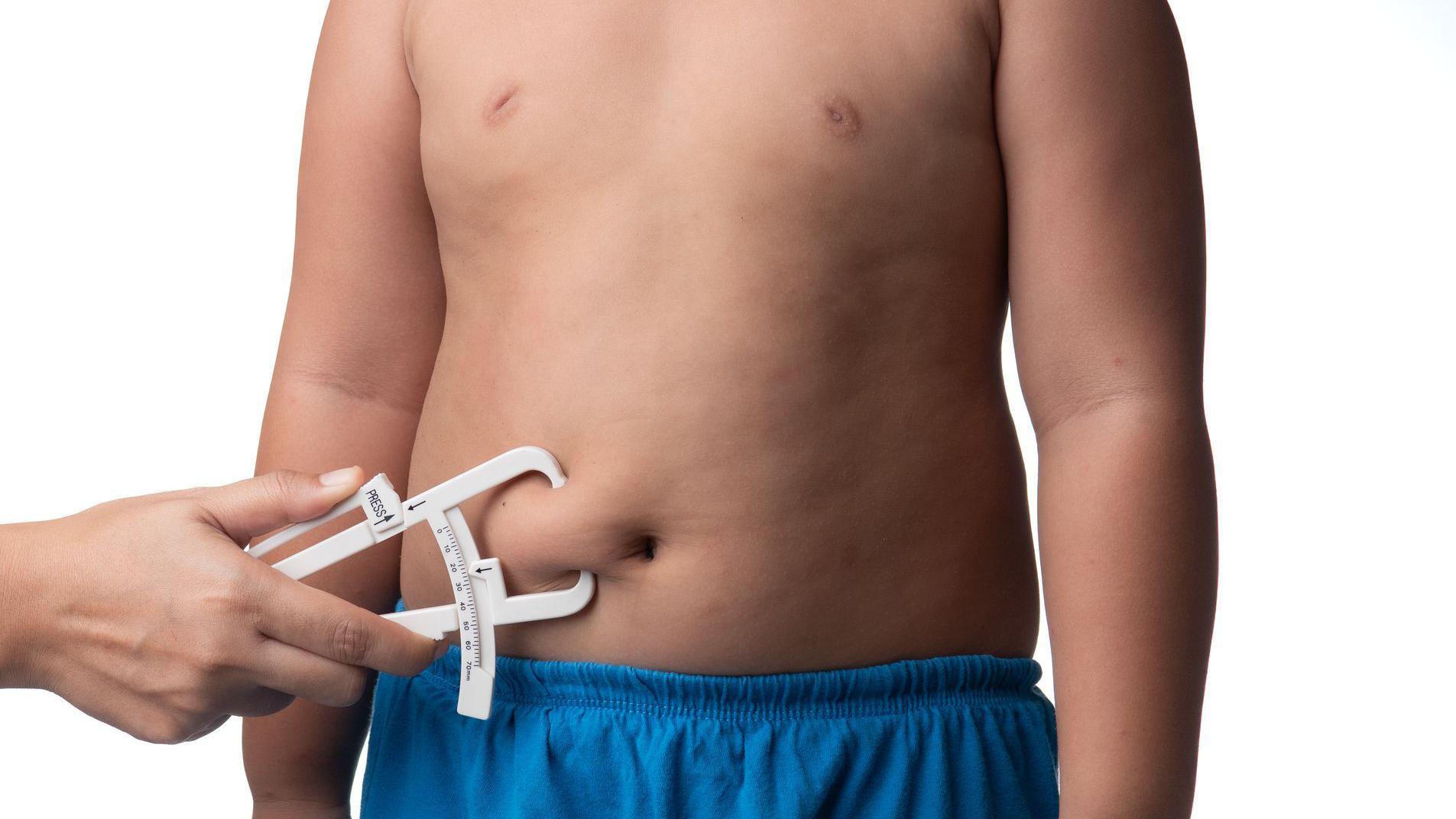 A doctor measures the belly of an overweight child