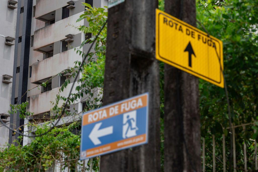 Duas placas em poste apontando para 'rotas de fuga'