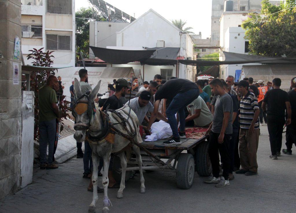 Un grupo de hombres coloca un cadáver sobre un carro tirado por un burro