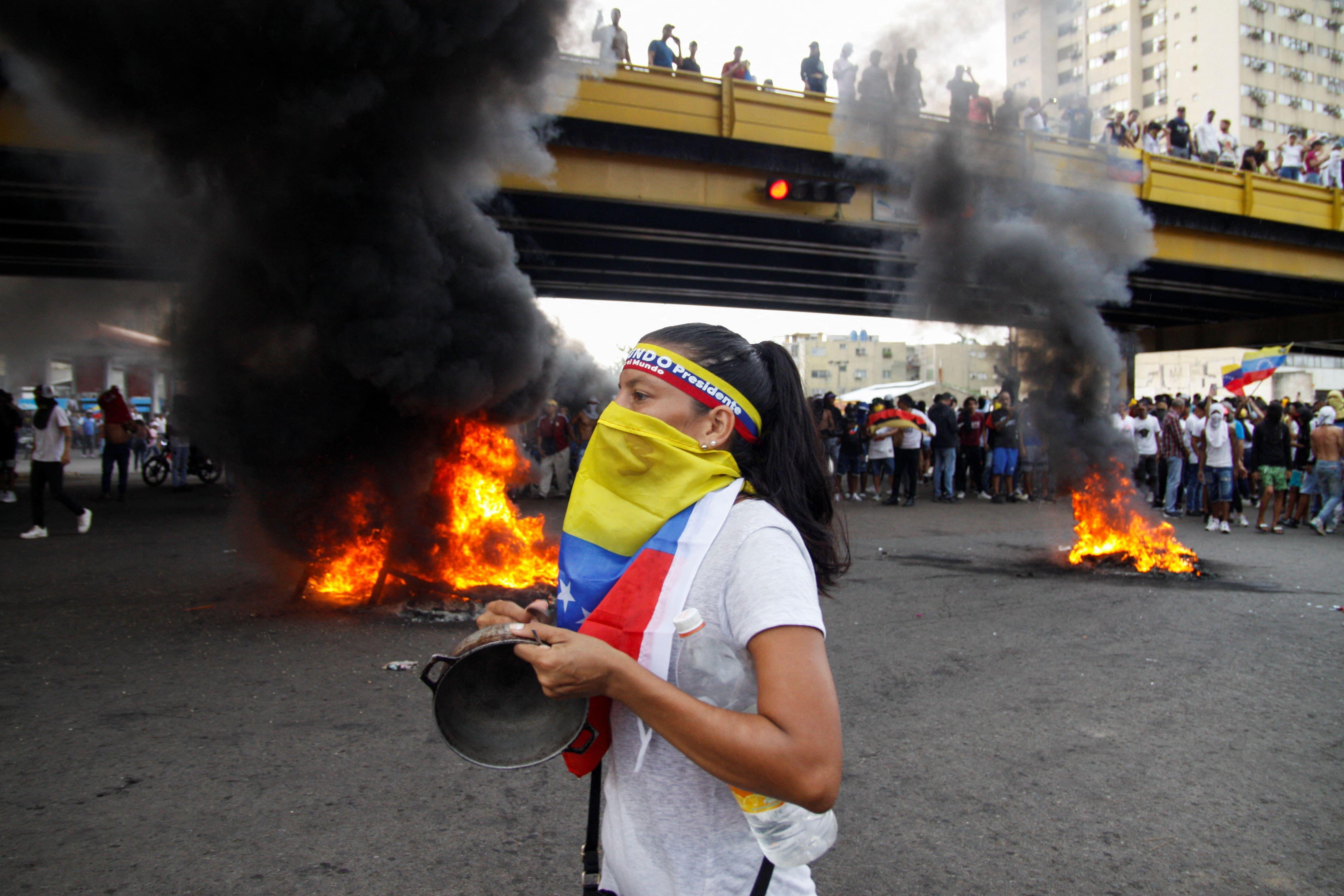 Mulher protesta com rosto vendado por bandeira da Venezuela