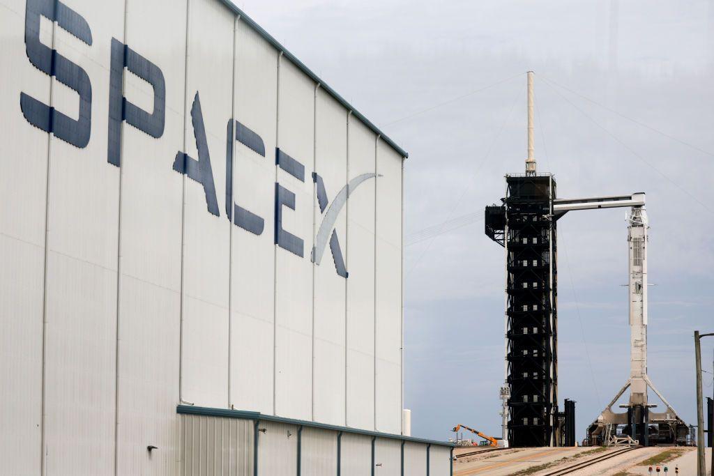 Un edificio de SpaceX y a lo lejos uno de sus cohetes.