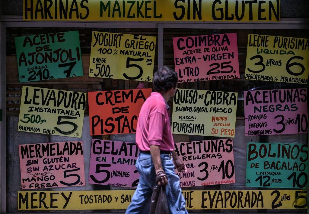 Un hombre camina frente a un comercio en Caracas dónde se anuncian todo tipo de productos.