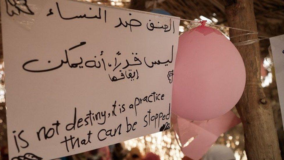 Una pancarta en árabe e inglés dice: "La violación no es un destino, es una práctica que se puede frenar"