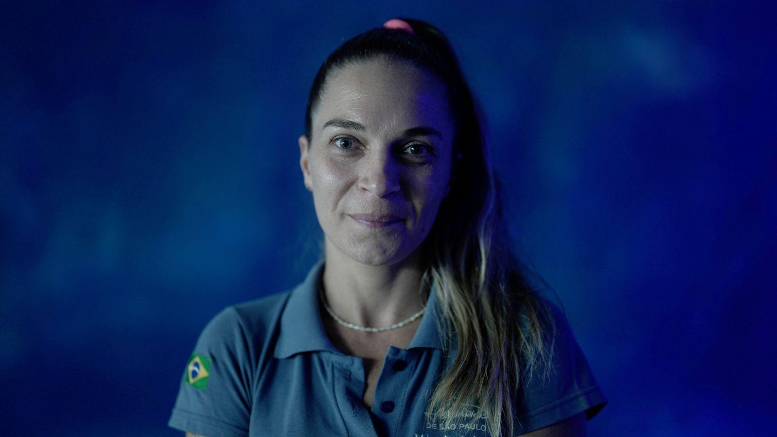 Laura Reisfeld usando camisa polo do Aquário de São Paulo com fundo azul de água da piscina onde ficam os ursos