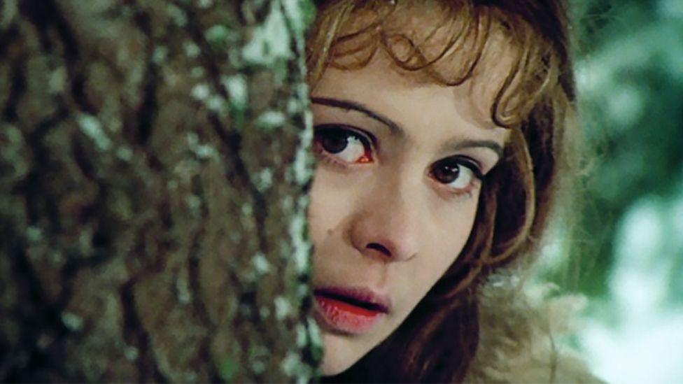 Libuse Safránková como Cenicienta, asomándose tras un árbol