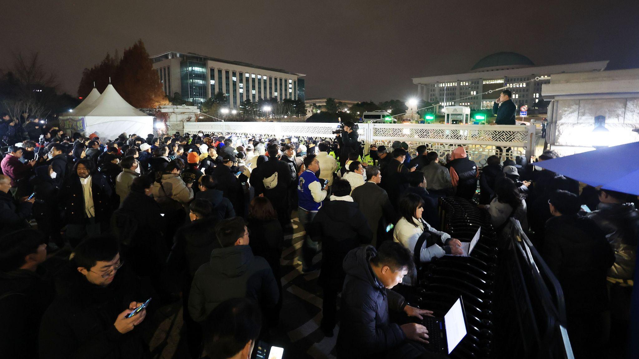 韓國首爾國會大樓外媒體記者與反對軍法統治群眾在警員防線前聚集（4/12/2024）