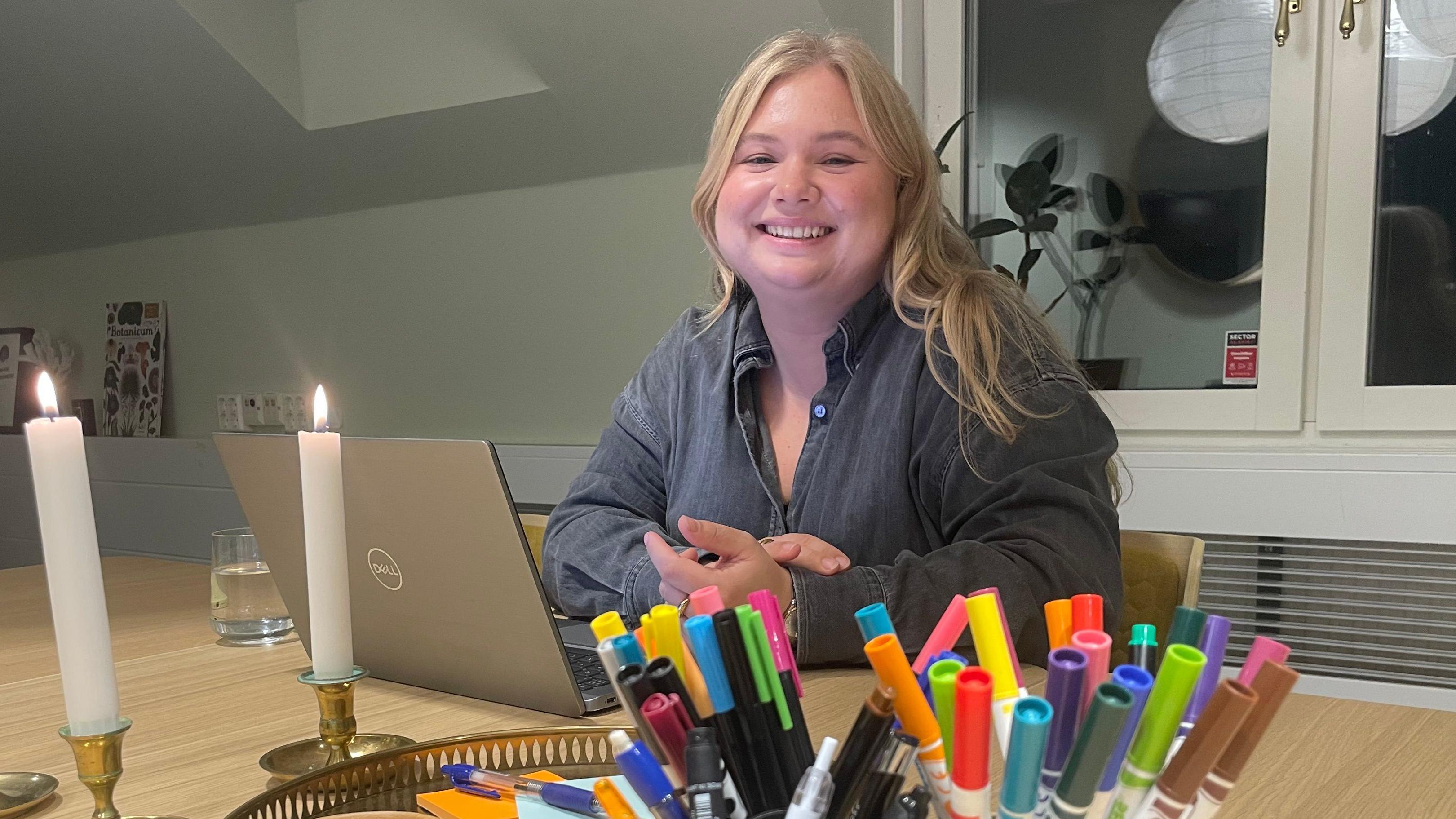 Johanna Göransson sitting with her laptop and smiling to the camera