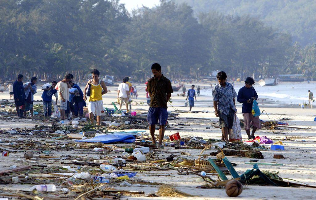 Pessoas caminham entre escombros ao longo da costa da praia de Pathong, na ilha de Phuket, sul da Tailândia, em 27 de dezembro de 2004, um dia depois que um maremoto devastou a costa