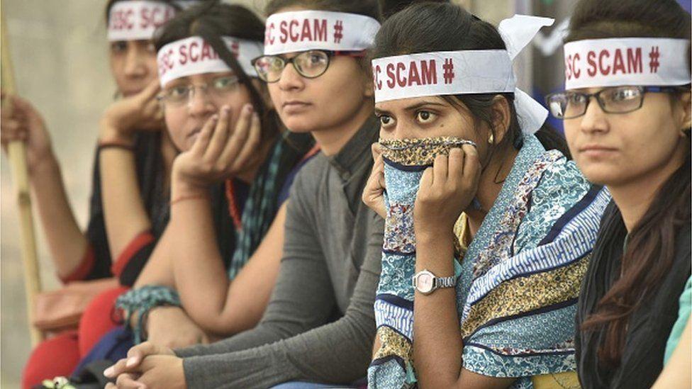 Mulheres sentadas usando faixas de protesto na cabeça