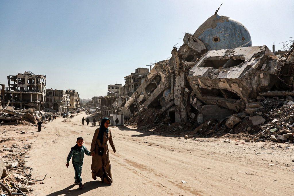 Una mujer y un niño caminan de la mano entre los edificios destruidos por ataques israelíes en Beit Lahia, una ciudad del norte de la Franja de Gaza, el 18 de febrero de 2025.  (Foto: Abd Khaled/Anadolu vía Getty Images) 