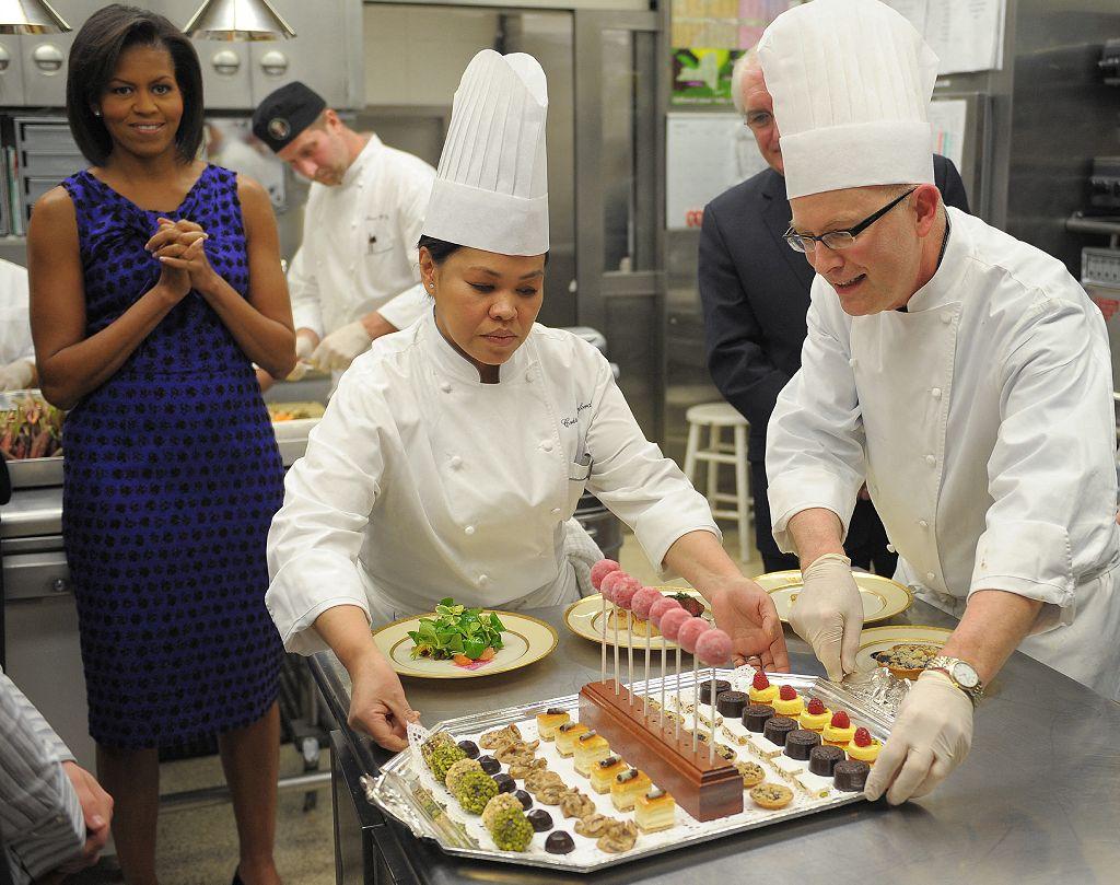 La primera dama Michelle Obama observa a Cristeta Comerford y el chef pastelero William Yosses con los postres para la Cena de los Gobernadores de 2009.