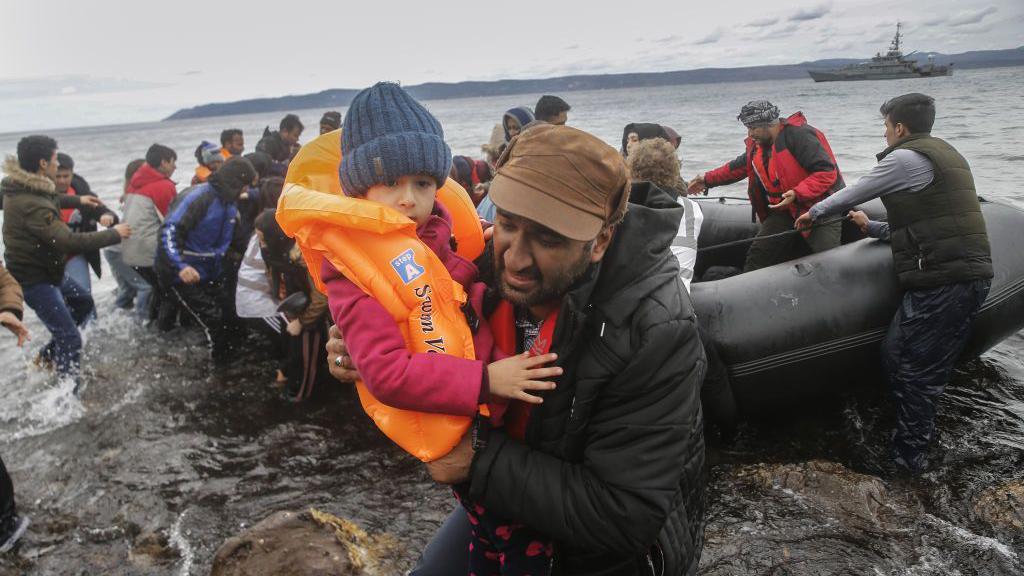 Migrantes chegam de barco a uma costa na ilha de Lesbos, na Grécia