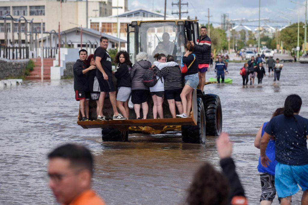 Varias personas siendo transportadas en la pala de una excavadora.