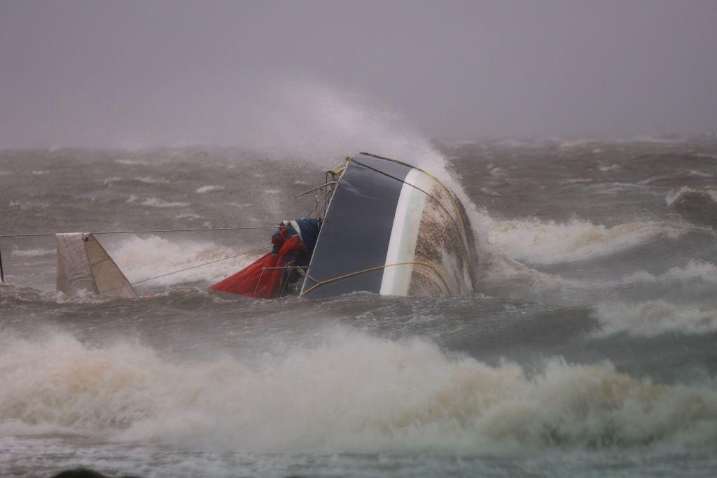 An overturned boat washes ashore as Hurricane Helene churns offshore.