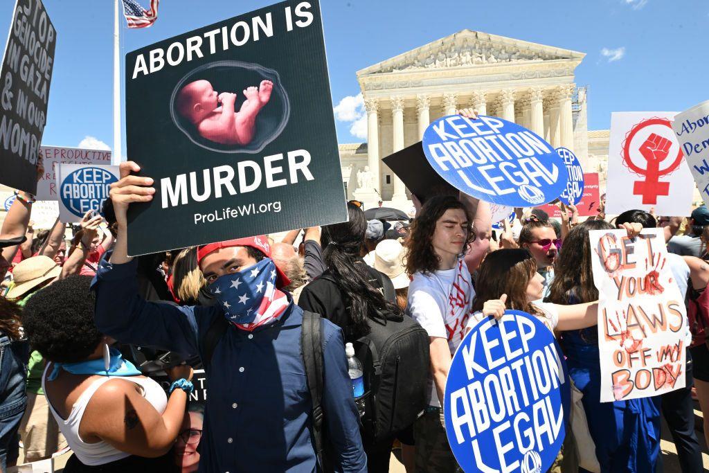 Un activista contra el aborto levanta su pancarta frente a una manifestación pro aborto ante el edificio de la Corte Suprema de EE.UU.