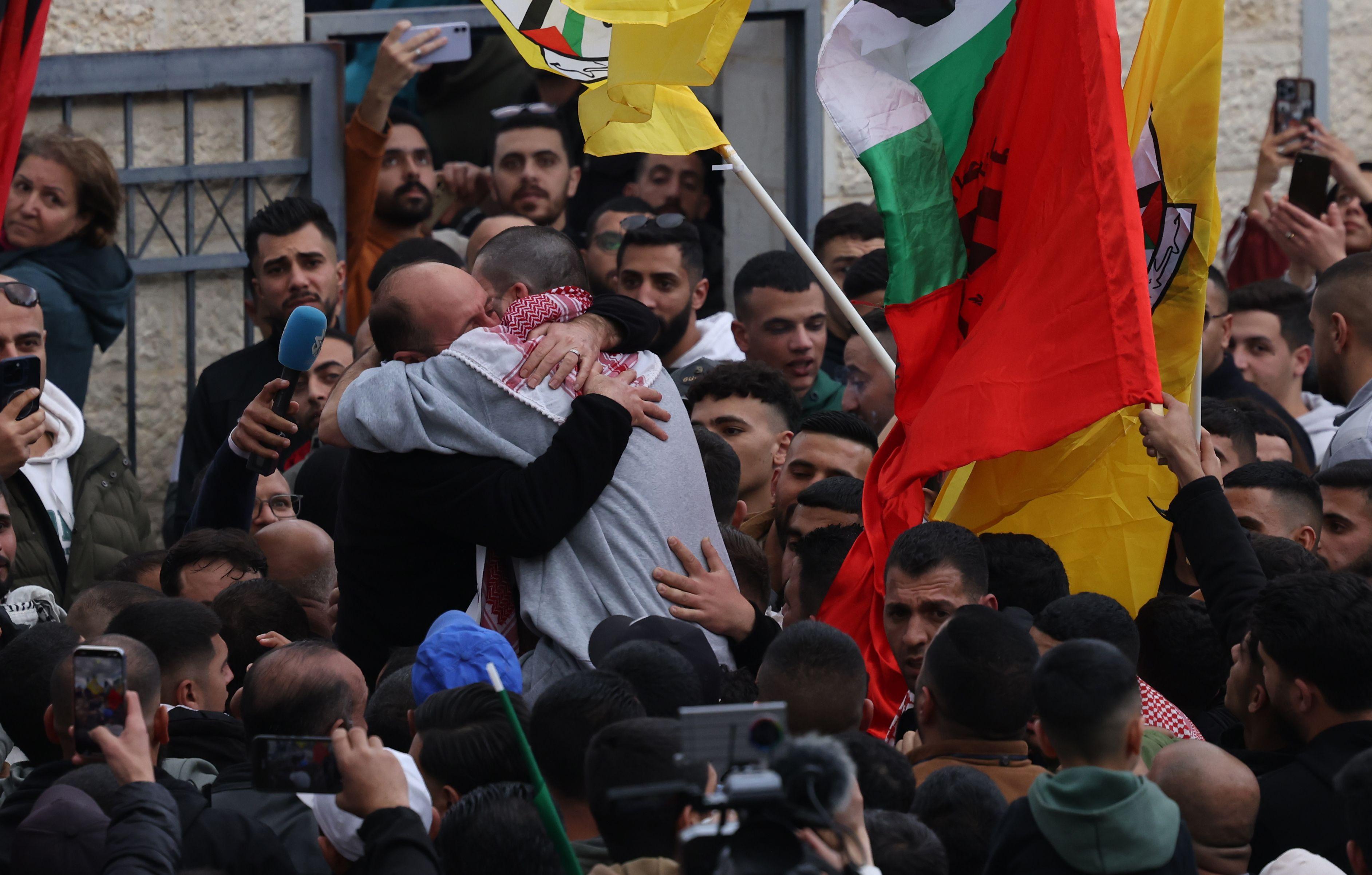 Zagrljaj dva muškarca u masi okruženih palestinskim zastavama