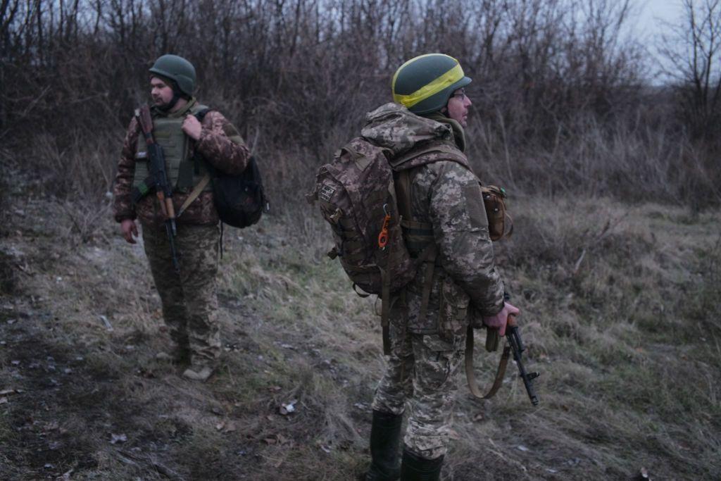 Soldados uniformizados e armados parados em área verde