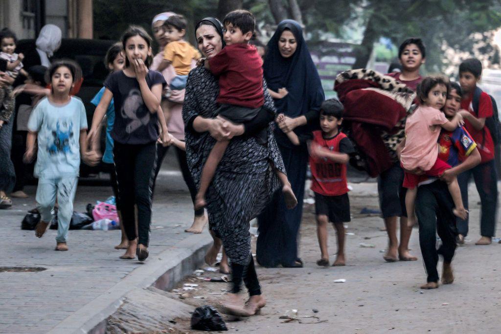 Mulheres aflitas caminhando com crianças na rua