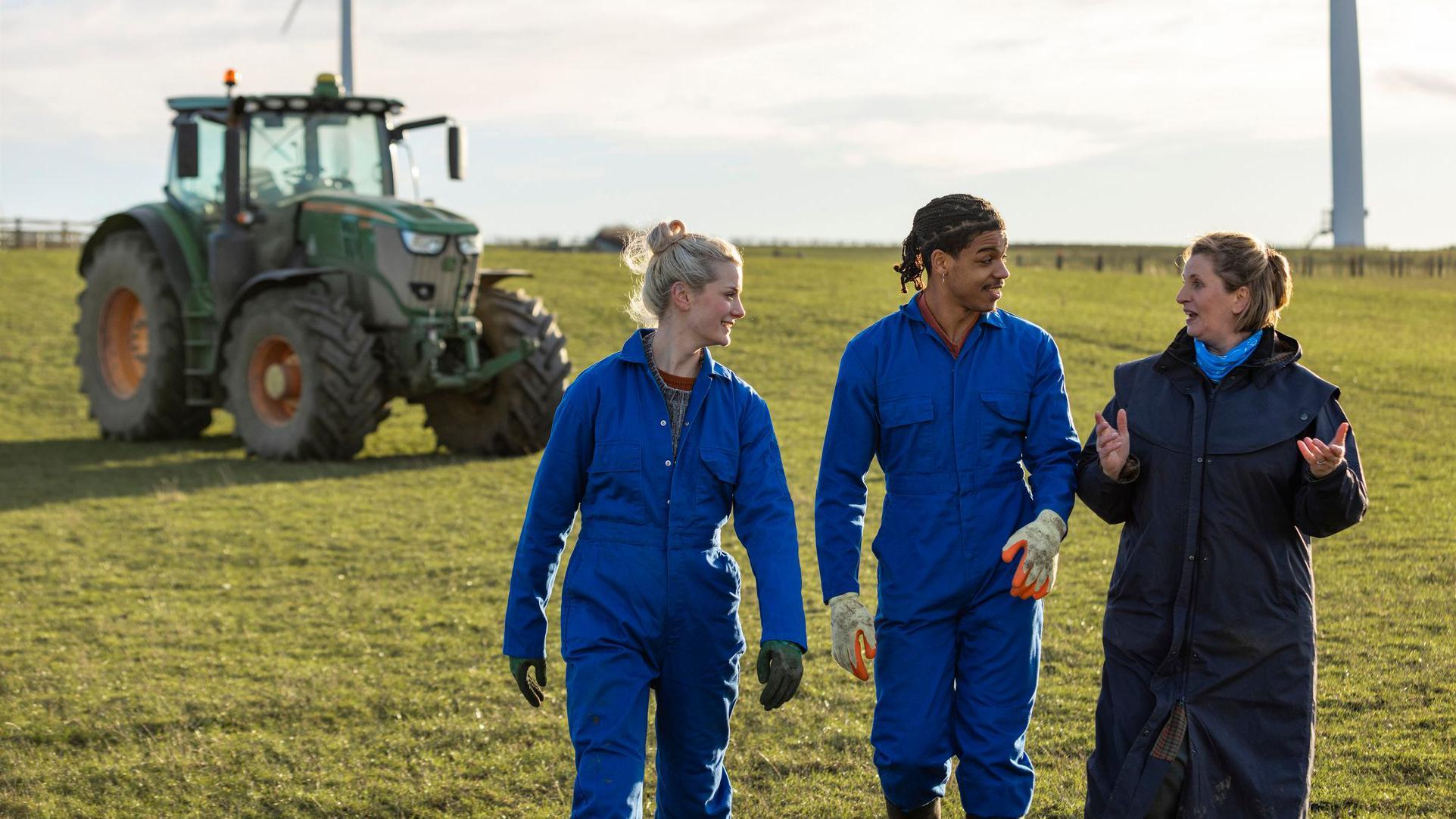 Dos jóvenes aprendices aprenden de una agricultora experimentada.